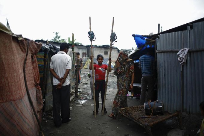 Drumpal Choudhary, 11, (C) a street performer, stands with wooden stilts outside his hut in a slum on the bank of Manahara River before leaving to perform on the streets of Kathmandu August 15, 2012. Drumpal and his siblings Shivani and Gchan, who came to Kathmandu from India 5 years ago, earn their living by performing tricks on the streets of Kathmandu. According to Drumpal, Shivani's older brother, they earn around $10 a day by performing tricks, which is not enough to feed their 10-member family living together in a small hut without a proper toilet or any basic needs. REUTERS/Navesh Chitrakar (NEPAL - Tags: SOCIETY IMMIGRATION POVERTY) Published: Srp. 15, 2012, 4:19 odp.