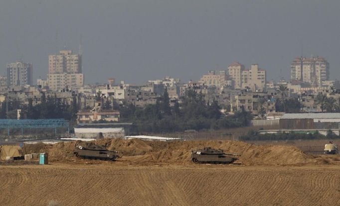 Israeli tanks stand in position near the border with northern Gaza, seen in the background November 15, 2012. A Hamas rocket killed three Israelis north of the Gaza Strip on Thursday, drawing the first blood from Israel as the Palestinian death toll rose to 13 and a military showdown lurched closer to all-out war with an invasion of the enclave. REUTERS/Ronen Zvulun (ISRAEL - Tags: POLITICS MILITARY CIVIL UNREST) Published: Lis. 15, 2012, 11:47 dop.