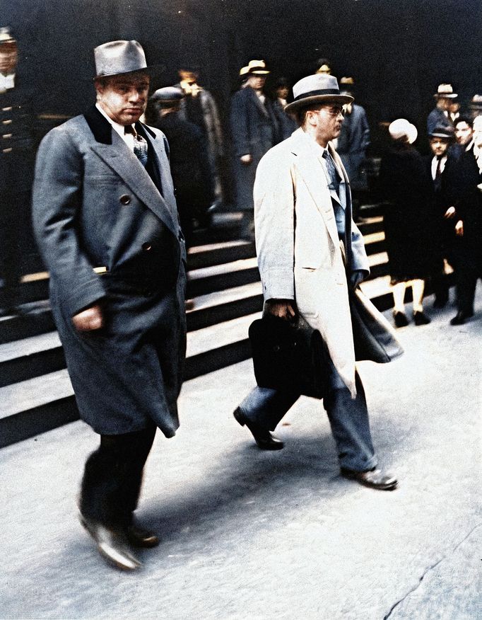 Al Capone se dívá na fotografy při odchodu od federálního soudu v Chicagu se svým právníkem Michaelem Ahernem 11. října 1931. Kolorovaná fotografie