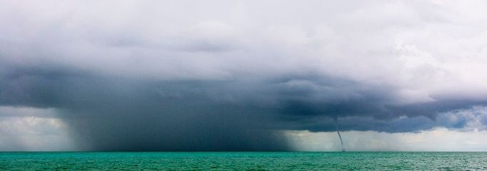 Inclement Weather at Sea Original caption:Storm clouds, heavy rain, and a waterspout are indicate rough weather to come.