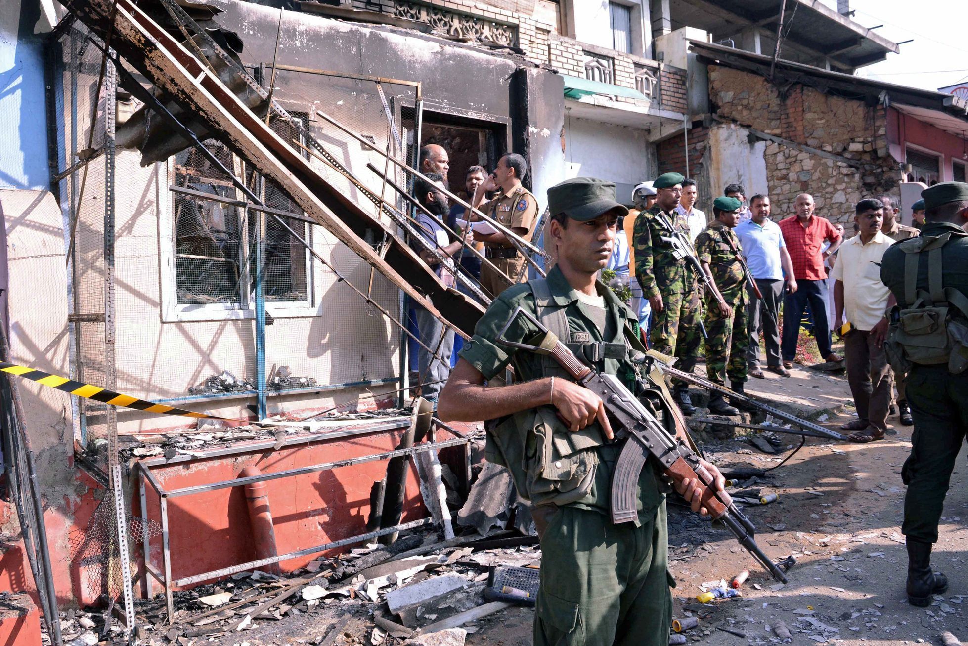 Srílanský policista hlídkuje u vypáleného domu.