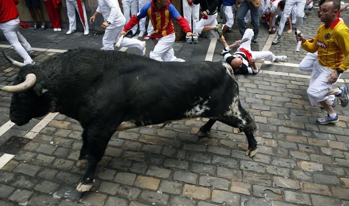 A runner falls near an El Pilar fighting bull at the Estafeta corner during the fourth running of the bulls at the San Fermin festival in Pamplona July 10, 2012. Several runners suffered light injuries in the fastest run (two minutes and twenty-two seconds) so far in this festival, according to local media. REUTERS/Susana Vera (SPAIN - Tags: SOCIETY ANIMALS) Published: Čec. 10, 2012, 7:46 dop.