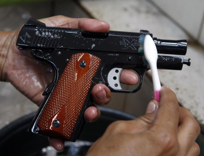 A gun factory worker uses a toothbrush to clean a newly produced caliber 45 pistol at Shooters Arms, a gun manufacturing company exporting different kinds of weapons to other countries, in Cebu city in central Philippines July 7, 2012. In the Philippines, they vote with their trigger fingers. Elections mean big business for illegal gunsmiths, who are looking forward to 2013 mid-term polls. With election-related violence commonplace, the Philippines imposes a ban on the carrying of guns for six months, from campaigning to the proclamation of winners. Picture taken July 7, 2012. To match Feature PHILIPPINES-GUNS/ REUTERS/Erik De Castro (PHILIPPINES - Tags: SOCIETY POLITICS BUSINESS CRIME LAW) Published: Čec. 29, 2012, 2:07 dop.