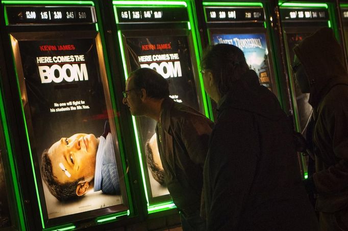 Robert Brown (L), a student at the World Services for the Blind (WSB) who is visually impaired due to Stargardt disease, gets close to a movie poster to read its words outside a theater in Little Rock, Arkansas January 4, 2013. Brown can read from a very short distance or using a magnifying lens. The WSB is a rehabilitation center for the blind or visually impaired which offers life skills and career training programs designed to help those enrolled achieve sustainable independence. Picture taken on January 4, 2013. REUTERS/Gaia Squarci (UNITED STATES - Tags: HEALTH EDUCATION SOCIETY) Published: Dub. 26, 2013, 2:16 odp.