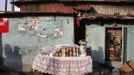 Vendor's kiosk offers goods for sale beside traditional colonial-era Board House in Congo Town of Freetown