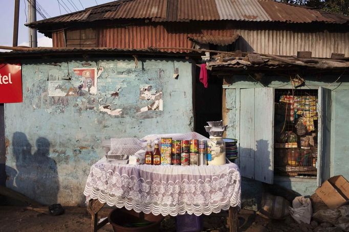 Vendor's kiosk offers goods for sale beside traditional colonial-era Board House in Congo Town of Freetown