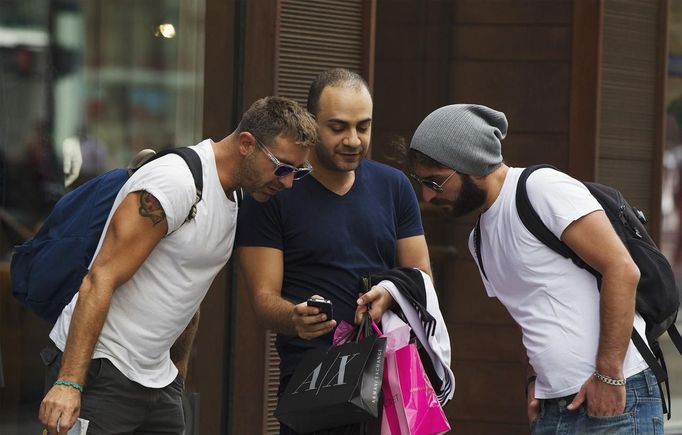 Two men look at another's Apple iPhone while shopping on 5th Avenue in New York, September 20, 2012. Apple's iPhone 5 goes on sale tomorrow as Apple works to increase it's market share in the mobile phone market. REUTERS/Lucas Jackson (UNITED STATES - Tags: BUSINESS SCIENCE TECHNOLOGY TELECOMS SOCIETY) Published: Zář. 20, 2012, 9:04 odp.