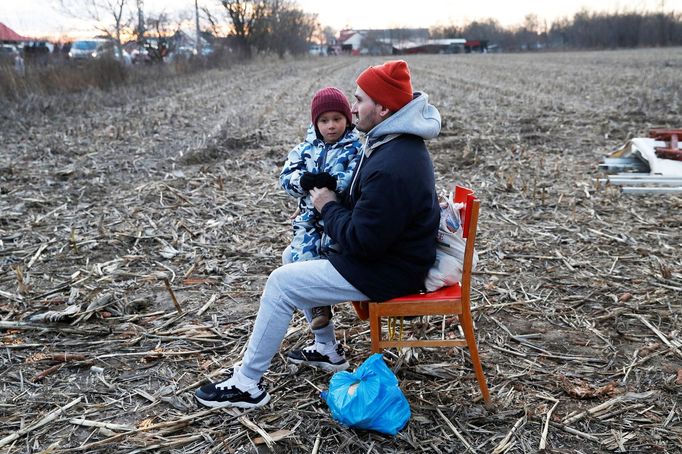 Záběr na sedícího muže s dítětem, kteří uprchli před válkou na Ukrajině. Fotografie byla pořízená nedaleko státní hranice u obce Tiszabecs v Maďarsku.