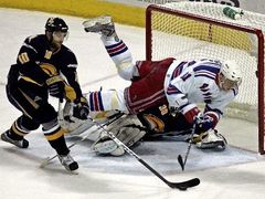 Útočník New Yorku Rangers Marcele Hossa (vpravo) padá přes gólmana Buffala Ryana Millera v pátém zápase čtvrtfinále NHL. S pukem odjíždí Henrik Tallinder.