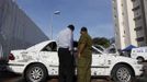 An Israeli soldier (R) and a civilian survey the damage to a car after a rocket fired from Gaza landed in the southern city of Ashdod November 16, 2012. Israel has started drafting 16,000 reserve troops, the military said on Friday, in a sign that violence could escalate further with Palestinian militants in the Gaza Strip. REUTERS/Amir Cohen (ISRAEL - Tags: POLITICS CIVIL UNREST MILITARY) Published: Lis. 16, 2012, 7:39 dop.