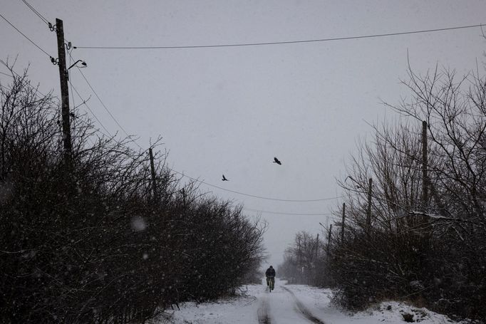 A man cycles along a road during snowfall near the front line in the Donetsk region, amid Russia’s attack on Ukraine, December 25, 2023.  REUTERS/Thomas Peter