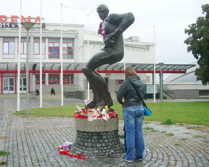 Pietní místo u pardubické arény. Pardubická hokejová socha dostala na krk českou šálu a obklopily ji hořící svíčky, květiny, české vlaječky a vzkazy, objevila se symbolicky i jedna hokejka. Nikoli poprvé, téměř na den přesně před čtyřmi lety (6.9.2007) tu hráči a fanoušci truchlili za obránce Martina Čecha, jenž zahynul při autonehodě během návratu z tréninku.