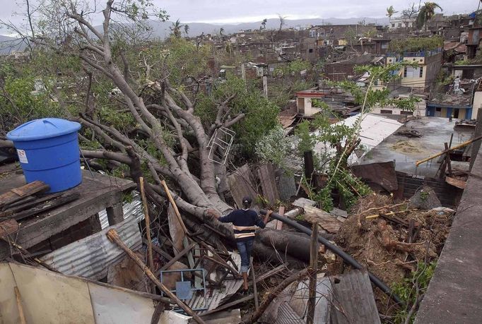 A woman looks at a fallen tree on top of her house after Hurricane Sandy hit Santiago de Cuba October 25, 2012. Strengthening rapidly after tearing into Jamaica and crossing the warm Caribbean Sea, Sandy hit southeastern Cuba early on Thursday with 105-mph winds that cut power and blew over trees across the city of Santiago de Cuba. Reports from the city of 500,000 people, about 470 miles (750 km) southeast of Havana spoke of significant damage, with many homes damaged or destroyed. REUTERS/Miguel Rubiera/Cuban Government National Information Agency-AIN/Handout (CUBA - Tags: ENVIRONMENT DISASTER) FOR EDITORIAL USE ONLY. NOT FOR SALE FOR MARKETING OR ADVERTISING CAMPAIGNS. THIS IMAGE HAS BEEN SUPPLIED BY A THIRD PARTY. IT IS DISTRIBUTED, EXACTLY AS RECEIVED BY REUTERS, AS A SERVICE TO CLIENTS Published: Říj. 25, 2012, 7:09 odp.