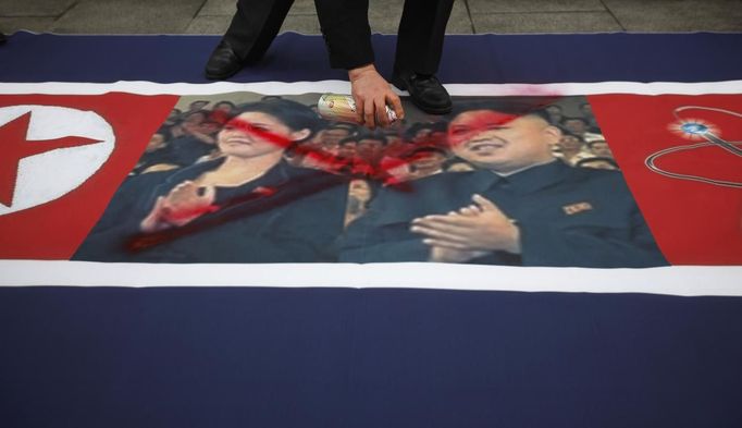 An activist from an anti-North Korea civic group defaces a North Korea flag depicting North's leader Kim Jong-un (R) and his wife Ri Sol-ju (L) during a rally against North Korea's nuclear test near the U.S. embassy in central Seoul February 12, 2013. North Korea conducted its third-ever nuclear test on Tuesday, a move likely to anger its main ally China and increase international action against Pyongyang and its new young leader, Kim Jong-un. U.N. Secretary-General Ban Ki-moon condemned North Korea's test, saying it was a "clear and grave violation" of U.N. Security Council resolutions. REUTERS/Kim Hong-Ji (SOUTH KOREA - Tags: CIVIL UNREST POLITICS) Published: Úno. 12, 2013, 8:01 dop.