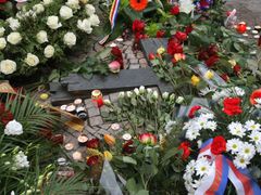 Nenápadný pomník Janu Palachovi a Janu Zajícovi vystupuje z dlažby jako ležící bronzový ohořelý kříž před kašnou u budovy Národního muzea. Dnes jej obklopily květiny, věnce a hořící svíčky.