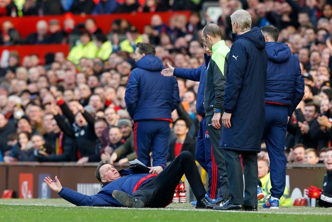 Manchester United manager Louis van Gaal lies on the side of the pitch to demonstrate a foul to the fourth official Mike Dean