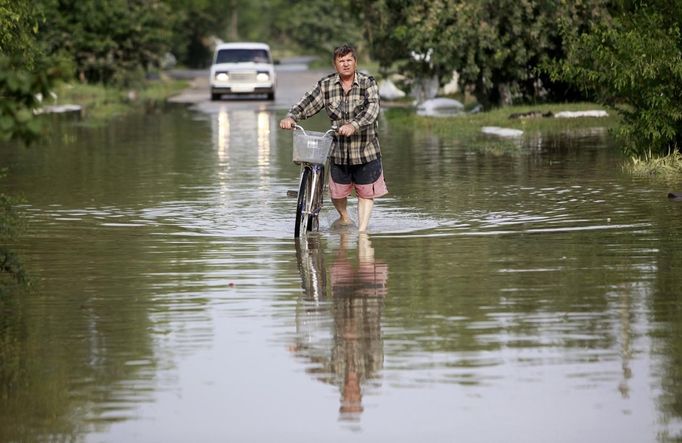 A local resident pulls his bicycle along a flooded street in the town of Krymsk in Krasnodar region, southern Russia, July 8, 2012. Russian President Vladimir Putin ordered investigators to find out if enough was done to prevent 144 people being killed in floods in southern Russia after flying to the region to deal with the first big disaster of his new presidency. REUTERS/Eduard Korniyenko (RUSSIA - Tags: DISASTER ENVIRONMENT POLITICS) Published: Čec. 8, 2012, 7:09 dop.