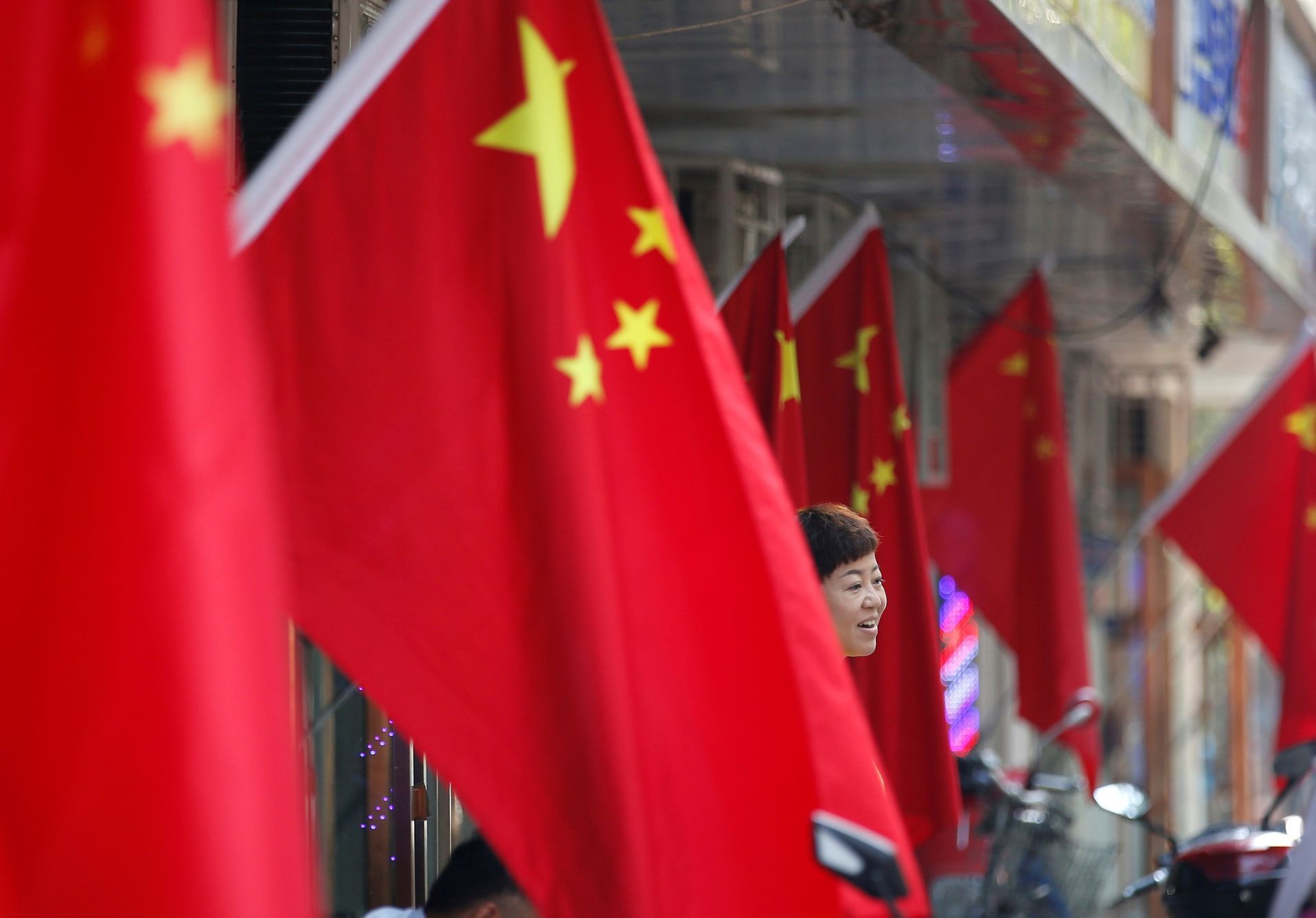 A woman stands amid Chinese national flags ahead of the 70th founding anniversary of People's Republic of China in Beijing