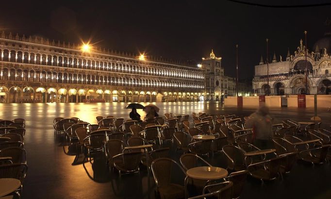 People sit on chairs in a flooded St Mark's Square at night during a period of seasonal high water in Venice November 1, 2012. The water level in the canal city rose to 140 cm (55 inches) above normal, according to the monitoring institute. REUTERS/Manuel Silvestri (ITALY - Tags: ENVIRONMENT SOCIETY TRAVEL) Published: Lis. 1, 2012, 7:49 dop.