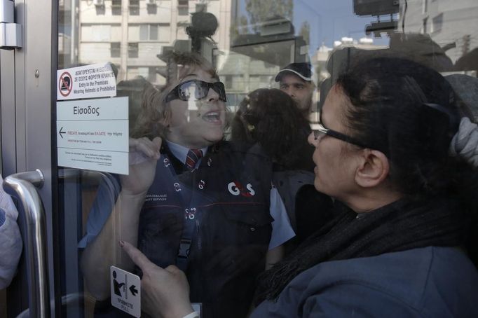 Nedočkaví klienti Laiki Bank se hlasitě dožadovali vstupu do banky. Ochranka je přes sklo vyzývala k trpělivosti.