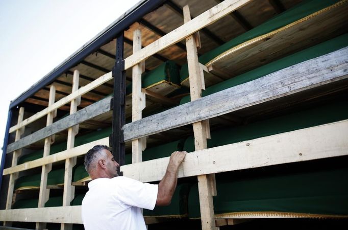 A Bosnian man looks for the name of his relatives in one of the three trucks carrying 520 coffins of newly identified victims of the 1995 Srebrenica massacre at Visoko morgue July 9, 2012. The bodies of the recently identified victims will be transported to the memorial centre in Potocari where they will be buried on July 11 marking the 17th anniversary of the massacre in which Bosnian Serb forces commanded by Ratko Mladic killed up to 8,000 Muslim men and boys and buried them in mass graves.REUTERS/Dado Ruvic (BOSNIA AND HERZEGOVINA - Tags: CIVIL UNREST ANNIVERSARY POLITICS OBITUARY) Published: Čec. 9, 2012, 11:16 dop.