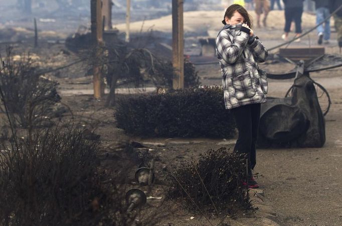 A girl stands among homes devastated by fire and the effects of Hurricane Sandy at the Breezy Point section of the Queens borough of New York October 30, 2012. Millions of people across the eastern United States awoke on Tuesday to scenes of destruction wrought by monster storm Sandy, which knocked out power to huge swathes of the nation's most densely populated region, swamped New York's subway system and submerged streets in Manhattan's financial district. REUTERS/Shannon Stapleton (UNITED STATES - Tags: ENVIRONMENT DISASTER) Published: Říj. 30, 2012, 2:03 odp.