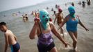 A woman, wearing a nylon mask, flashes a sign as she walks towards the shore during her visit to a beach in Qingdao, Shandong province July 6, 2012. The mask, which was invented by a woman about seven years ago, is used to block the sun's rays. The mask is under mass production and is on sale at local swimwear stores. REUTERS/Aly Song (CHINA - Tags: SOCIETY ENVIRONMENT TRAVEL TPX IMAGES OF THE DAY) Published: Čec. 6, 2012, 6:30 odp.