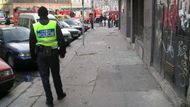 Policista hlídá prostor před restaurací "U Arbesa", aby tam lidé nemohli.
