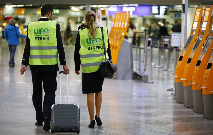 Two members of German air carrier Lufthansa, wearing their cabin crew union (UFO) strike vests, walk through the Lufthansa terminal at the Fraport airport in Frankfurt, August 31, 2012. Lufthansa passengers face widespread flight disruption from Friday after cabin crew representatives said they would start a series of strikes over pay and cost-cutting measures at Germany's largest airline. The UFO union, which represents around two-thirds of Lufthansa's 19,000 cabin crew, late on Thursday called on its members to strike from 0300 GMT to 1100 GMT on Friday in Frankfurt. REUTERS/Kai Pfaffenbach (GERMANY - Tags: BUSINESS EMPLOYMENT CIVIL UNREST TRANSPORT) Published: Srp. 31, 2012, 4:19 dop.