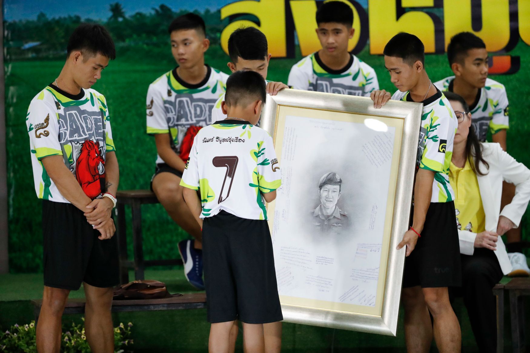 Thajští fotbalisté a jejich trenér (vlevo) uctili krátce po svém vysvobození Samana Gunana, který zemřel během záchranné akce.