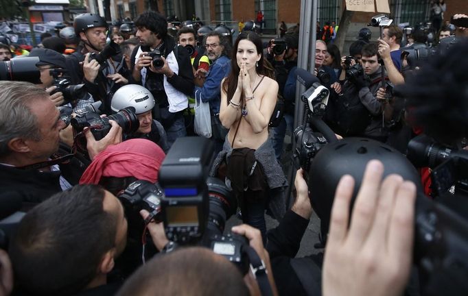 A topless protester is surrounded by cameramen during an anti-austerity demonstration outside the Spanish parliament in Madrid, September 25, 2012. Anti-austerity demonstrators protested in Madrid ahead of the government's tough 2013 budget that will cut into social services as the country teeters on the brink of a bailout. REUTERS/Paul Hanna (SPAIN - Tags: POLITICS CIVIL UNREST BUSINESS) Published: Zář. 25, 2012, 6:25 odp.