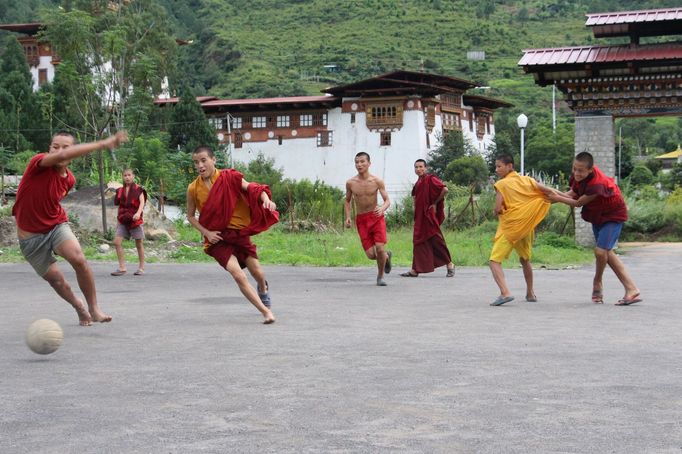 Mladí mniši hrají fotbal v Bhútánu – v zemi, jež měří místo hrubého domácího produktu (HDP) své „hrubé národní štěstí“, GNH (Punakha, 2014).