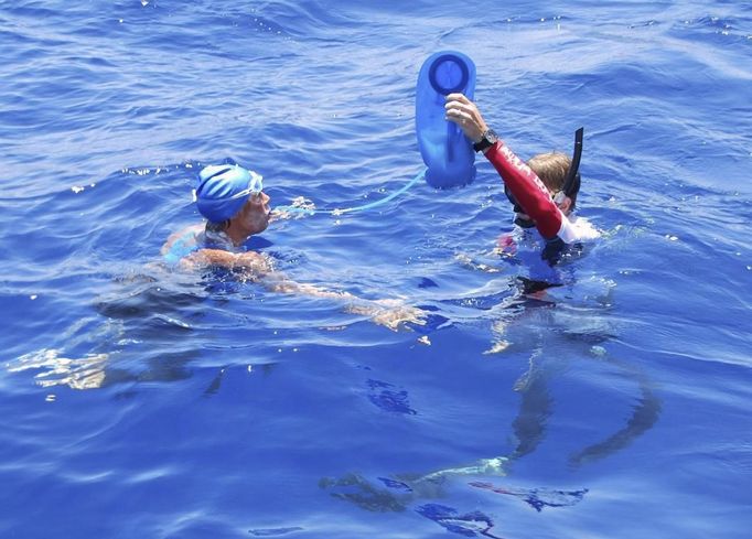 Endurance swimmer Diana Nyad is hydrated by a crew member in the Florida Straits between Cuba and the Florida Keys in this August 20, 2012 handout photo. After being delayed by a weather squall line late Sunday night and early Monday morning, her team reported that Nyad was back on course in her effort to be the first swimmer to transit the Florida Straits from Cuba to the Keys without a shark cage.REUTERS/Christi Barli/Diana Nyad/Florida Keys News Bureau/Handout. (UNITED STATES - Tags: PROFILE SPORT SOCIETY) NO SALES. NO ARCHIVES. FOR EDITORIAL USE ONLY. NOT FOR SALE FOR MARKETING OR ADVERTISING CAMPAIGNS. THIS IMAGE HAS BEEN SUPPLIED BY A THIRD PARTY. IT IS DISTRIBUTED, EXACTLY AS RECEIVED BY REUTERS, AS A SERVICE TO CLIENTS Published: Srp. 20, 2012, 10:15 odp.