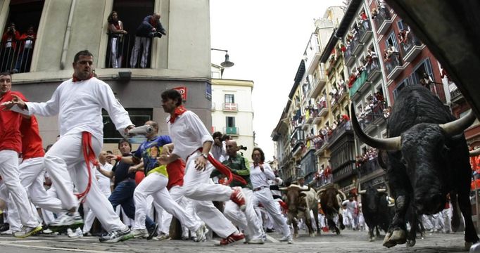 A Fuente Ymbro fighting bull slides towards the fence as runners sprint alongside at the Estafeta corner during the fifth running of the bulls of the San Fermin festival in Pamplona July 11, 2012. Several runners suffered light injuries in a run that lasted three minutes and twelve seconds, according to local media. REUTERS/Susana Vera (SPAIN - Tags: SOCIETY ANIMALS) Published: Čec. 11, 2012, 8:49 dop.