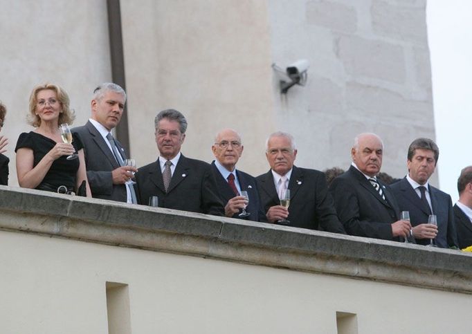 Prezidenti Srbska, Rakouska, Itálie, Česka, Albánie a Bulharska (zleva doprava) sledují přehlídku hradních stráží v dobových uniformách. Prezidenty sleduje nedobová bezpečnostní kamera.