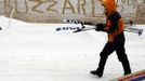 A pedestrian carries their skis past the word "Blizzard" written in the snow stuck to the side of a building in Boston, Massachusetts February 9, 2013 during a winter blizzard. REUTERS/Brian Snyder (UNITED STATES - Tags: ENVIRONMENT) Published: Úno. 9, 2013, 5:40 odp.