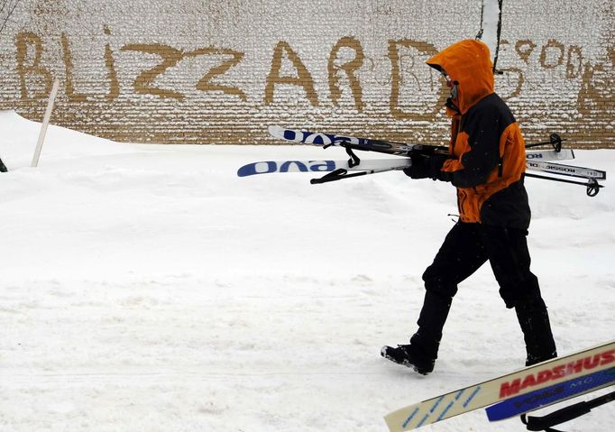 A pedestrian carries their skis past the word "Blizzard" written in the snow stuck to the side of a building in Boston, Massachusetts February 9, 2013 during a winter blizzard. REUTERS/Brian Snyder (UNITED STATES - Tags: ENVIRONMENT) Published: Úno. 9, 2013, 5:40 odp.