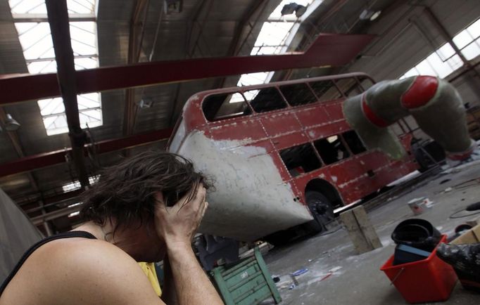 Artist David Cerny sits at a factory in Prague as he works on his project to transform a London bus into a robotic sculpture May 22, 2012. The bus, which Cerny hopes could become an unofficial mascot of the London 2012 Olympic Games, does push-ups with the help of an engine powering a pair of robotic arms and the motion is accompanied by a recording of sounds evoking tough physical effort. It will be parked outside the Czech Olympic headquarters in London for the duration of the Games. Picture taken May 22, 2012. REUTERS/Petr Josek (CZECH REPUBLIC - Tags: SOCIETY SPORT OLYMPICS TRANSPORT) Published: Čec. 22, 2012, 5:53 odp.