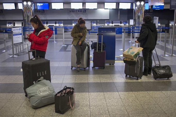 Travelers from South Korea use their mobile phones after arriving to an empty terminal as flights were cancelled at LaGuardia airport in New York October 28, 2012. Tens of millions of East Coast residents scrambled on Sunday to prepare for Hurricane Sandy, which could make landfall as the largest storm to hit the United States, bringing battering winds, flooding and even heavy snow. REUTERS/Adrees Latif (UNITES STATES - Tags: TRANSPORT DISASTER ENVIRONMENT TRAVEL)