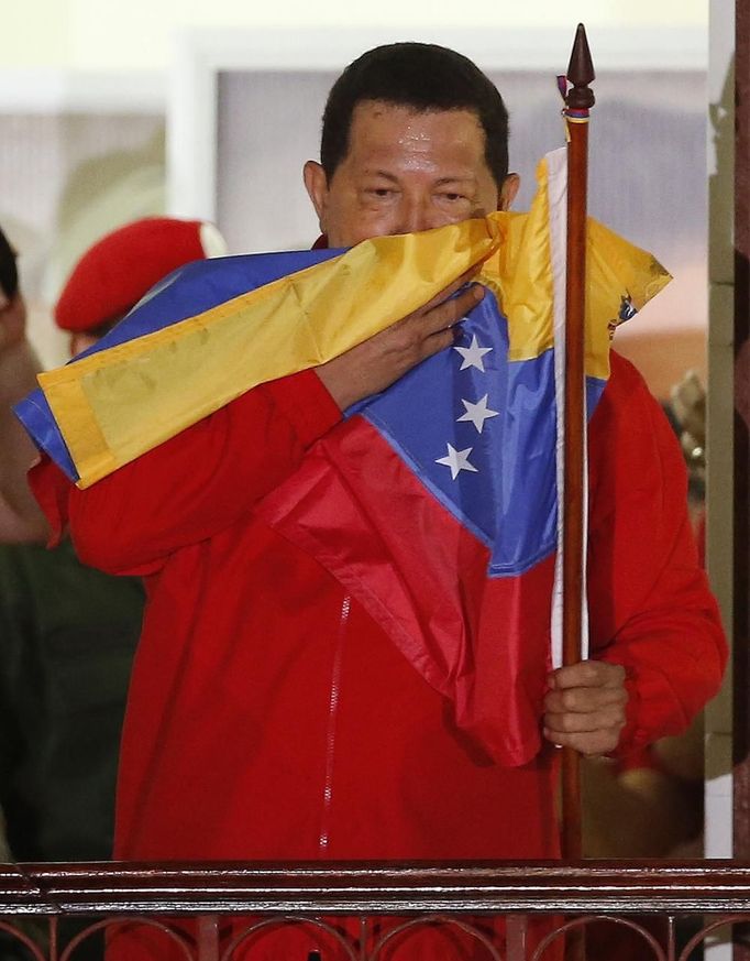 Venezuelan President Hugo Chavez hugs the national flag while celebrating from a balcony at the Miraflores Palace in Caracas October 7, 2012. Venezuela's socialist President Chavez won re-election in Sunday's vote with 54 percent of the ballot to beat opposition challenger Henrique Capriles. REUTERS/Jorge Silva (VENEZUELA - Tags: POLITICS ELECTIONS) Published: Říj. 8, 2012, 5:06 dop.