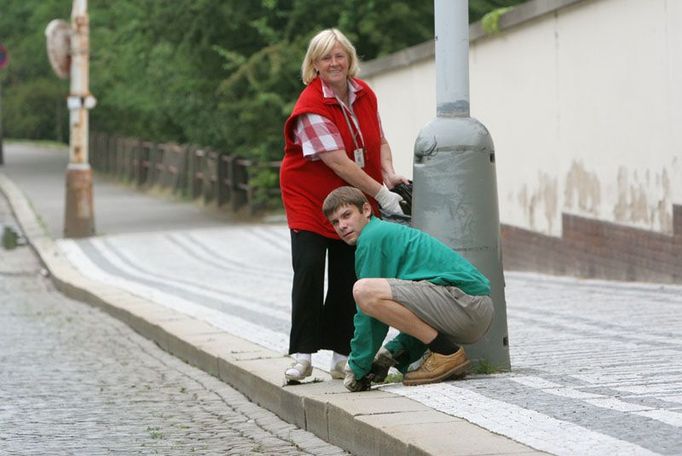 Pracovníci Ministerstva zahraničních věcí vytrhávají trávu z chodníku na ulici Keplerova.