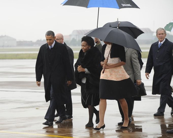 U.S. President Barack Obama (C) and former U.S. President George Bush (R) are greeted by officials on their arrival at Air Force Base Waterkloof, Pretoria in this handout picture provided by the South African Government Communication and Information System (GCIS) on December 10, 2013.