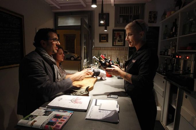 Italian restaurant owner Donella Faggioli (R) examines bottles of liquor customers want to exchange for a meal at the "L'e'Maiala" restaurant in Florence October 6, 2012. At walking distance from the tourist cafeterias around Palazzo Vecchio, Faggioli and her husband Frank are busy bartering wine and potatoes for a meal of Tuscan "pici" pasta with pork sauce. The neighbourly couple have recently launched a 40-seat restaurant in Florence that allows customers to exchange vegetables and used goods for a traditional Tuscan dinner, in a way to encourage people to dine out despite the recession. Picture taken October 6, 2012. To match story ITALY-BARTER/ REUTERS/Alessandro Bianchi (ITALY - Tags: SOCIETY BUSINESS FOOD) Published: Říj. 10, 2012, 9:34 dop.