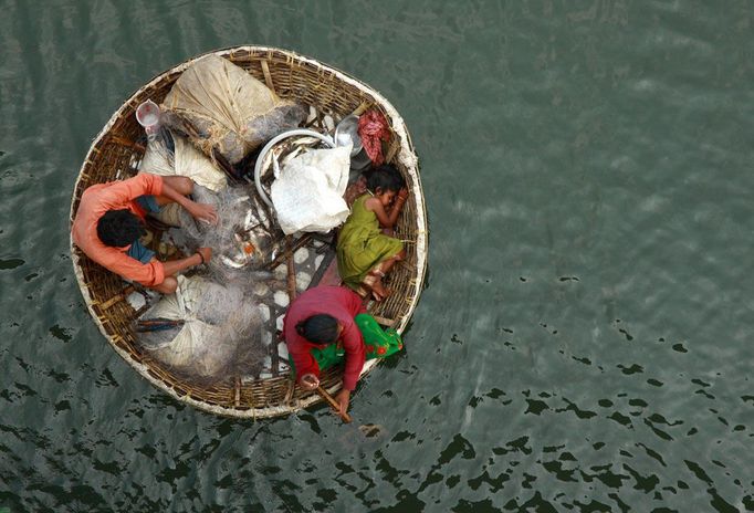 Rybář připravuje síť, zatímco jeho žena pádluje ve vodách řeky Periyar na periferii města Kochi v jižní Indii, 5. Ledna 2011. REUTERS/Sivaram V