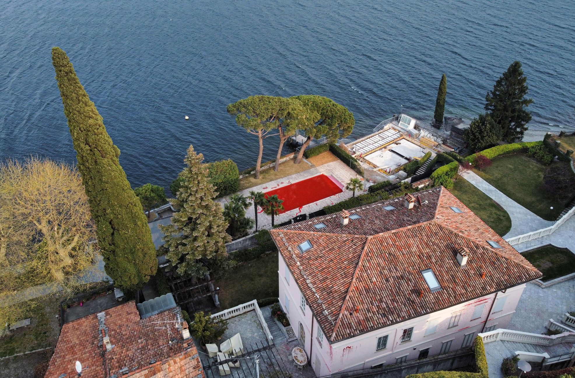 Solovjovova vila s rudými cákanci na omítce a s bazénem zbarveným do ruda v Itálii u jezera Como.
