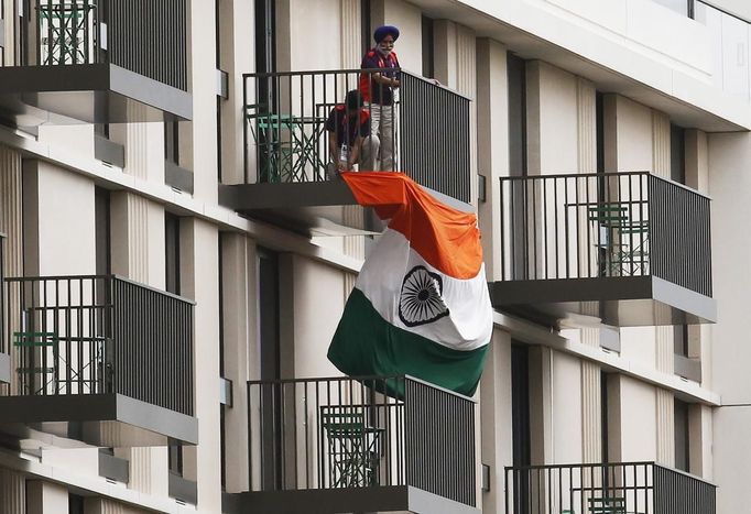 Men hang an Indian flag from a balcony in the Athletes' Village, ahead of the Olympic Games in the London 2012 Olympic Park at Stratford in London July 17, 2012. REUTERS/Luke MacGregor (BRITAIN - Tags: SPORT OLYMPICS) Published: Čec. 17, 2012, 5:33 odp.