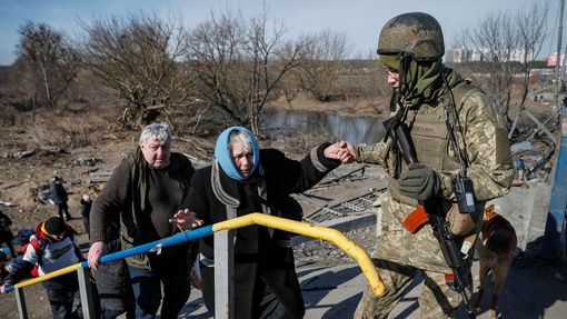 Ukrajinský voják pomáhá starší ženě při evakuaci z města Irpiň.