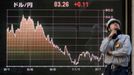 Stavební dělník stojící před elektronickou tabulí makléřské společnosti, která zobrazuje graf s pohybem loňského kurzu japonského jenu vůči americkému dolaru.