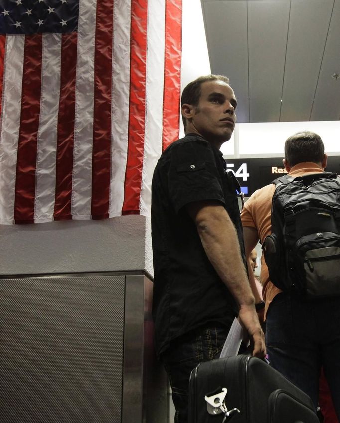 Luis Salgado, nicknamed Chucho, waits in line at U.S. Immigration upon arriving at Miami airport on a direct flight from Havana, March 13, 2013. Chucho was granted a U.S. visa based on his father's status as legal resident in Texas, and he was reunited in Miami with his father, Jesus Salgado, who had escaped Cuba on a frail boat ten years earlier. The Salgados are among many Cubans taking advantage of Cuba's new travel policy in place since last January, which allows citizens to leave the country with just a passport and no need for much-hated exit visas required since 1961. Picture taken March 13, 2013. REUTERS/Desmond Boylan (UNITED STATES - Tags: POLITICS SOCIETY) Published: Dub. 11, 2013, 1:43 odp.