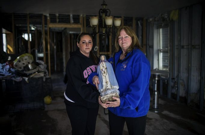 Alice Lauro and her daughter Margaret pose for a photograph as they hold a statue of the Blessed Mother Mary which was one of the few items to survive intact when their home flooded on Rome Avenue, Staten Island November 14, 2012. Lauro and her husband were planning on moving away from Staten Island before Hurrican Sandy struck but now she says, "we would not live anywhere else, the people of Staten Island saved us." Picture taken November 14, 2012. REUTERS/Mike Segar (UNITED STATES - Tags: DISASTER ENVIRONMENT RELIGION) ATTENTION EDITORS PICTURE 17 OF 19 FOR PACKAGE 'SURVIVING SANDY' SEARCH 'SEGAR SANDY' FOR ALL PICTURES Published: Lis. 20, 2012, 3:31 odp.